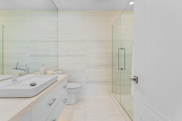 bathroom featuring toilet, tile walls, a stall shower, and vanity