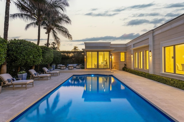 pool at dusk featuring a fenced in pool and a patio area