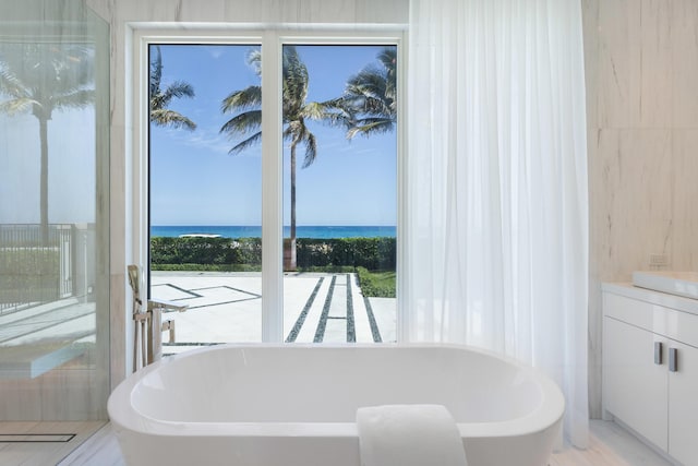 full bathroom featuring a freestanding tub, a water view, and vanity