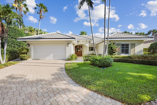 view of front of house with a tiled roof, a front yard, stucco siding, decorative driveway, and a garage