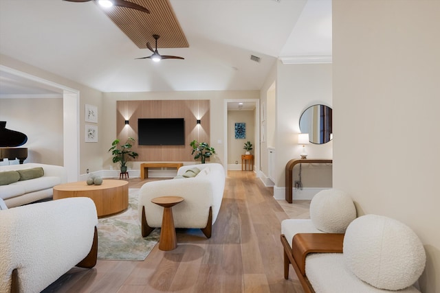 living area with visible vents, crown molding, ceiling fan, lofted ceiling, and light wood-style flooring