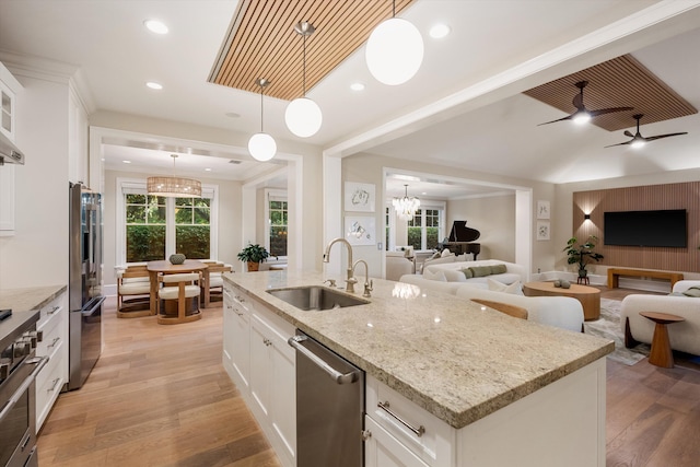 kitchen with open floor plan, premium appliances, light wood finished floors, and a sink