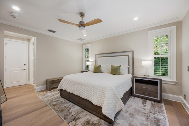 bedroom with crown molding, baseboards, visible vents, and light wood finished floors