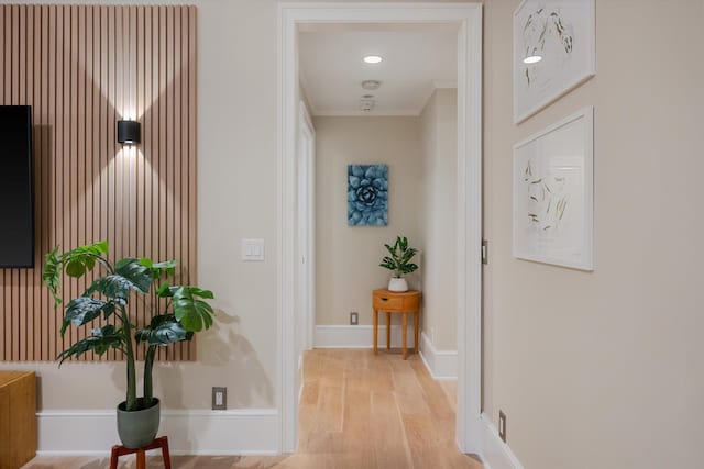 corridor with light wood-style flooring, baseboards, and ornamental molding