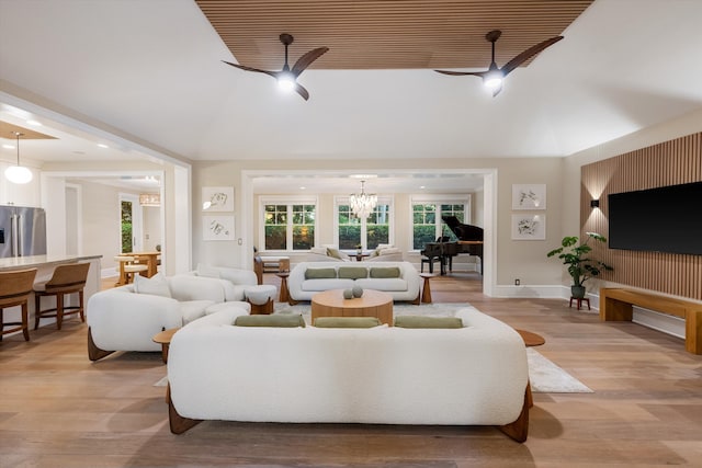 living area with an inviting chandelier, light wood-style floors, baseboards, and high vaulted ceiling