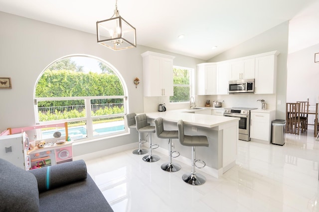 kitchen with a breakfast bar area, light countertops, a peninsula, white cabinets, and stainless steel appliances