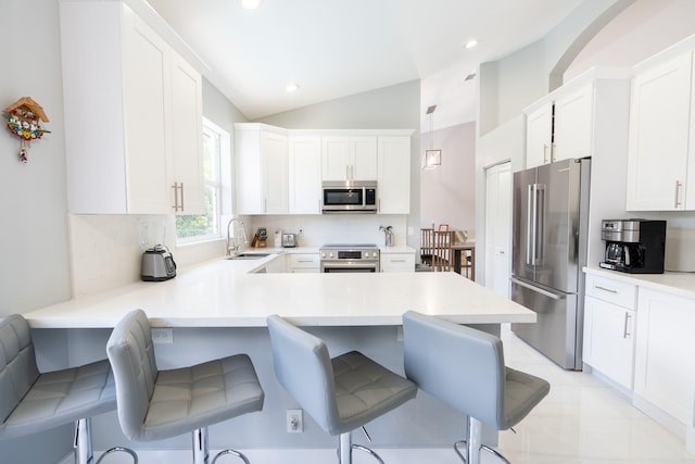 kitchen with light countertops, vaulted ceiling, a peninsula, stainless steel appliances, and a sink