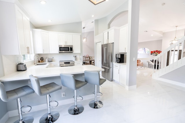 kitchen with a sink, a kitchen breakfast bar, appliances with stainless steel finishes, and white cabinets