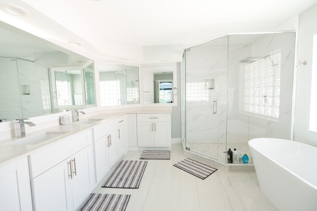 full bath with vanity, a freestanding tub, and a marble finish shower