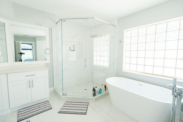 full bath featuring vanity, a soaking tub, and a marble finish shower