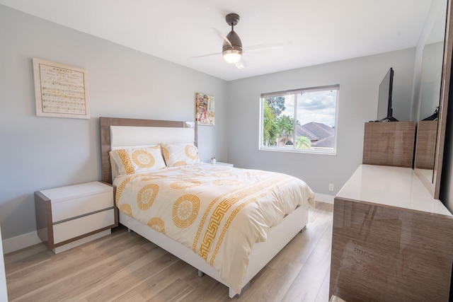 bedroom with a ceiling fan, baseboards, and light wood finished floors