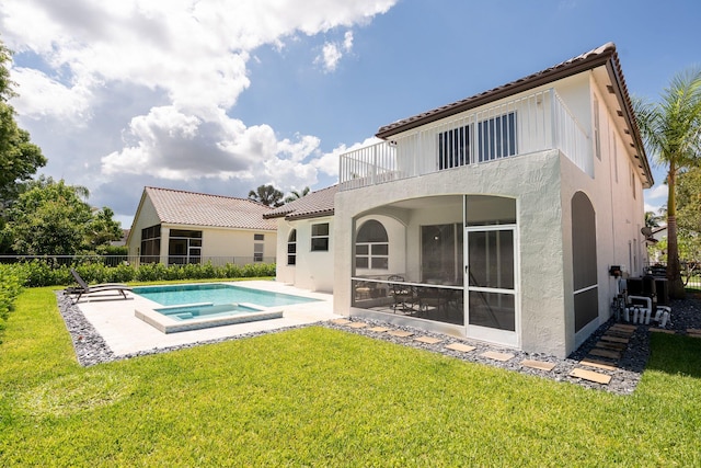 rear view of house featuring a balcony, an in ground hot tub, a yard, a tiled roof, and a patio area