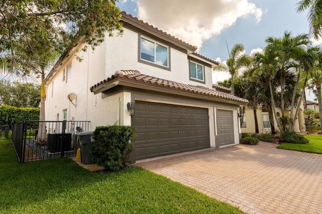 mediterranean / spanish-style home featuring a tile roof, stucco siding, a front yard, and a garage