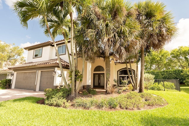 mediterranean / spanish-style house with a front lawn, fence, concrete driveway, stucco siding, and an attached garage