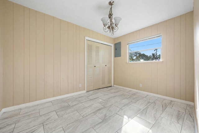 unfurnished bedroom with electric panel, a closet, baseboards, and an inviting chandelier