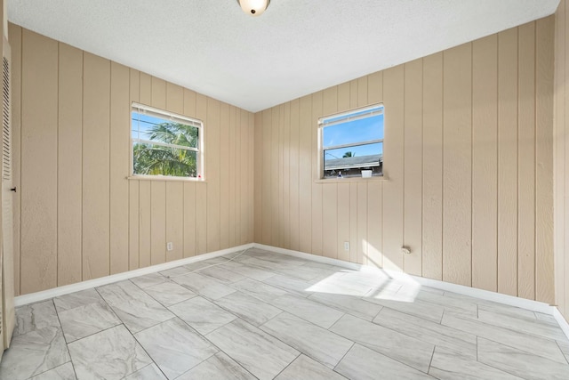 empty room featuring baseboards, a wealth of natural light, and a textured ceiling