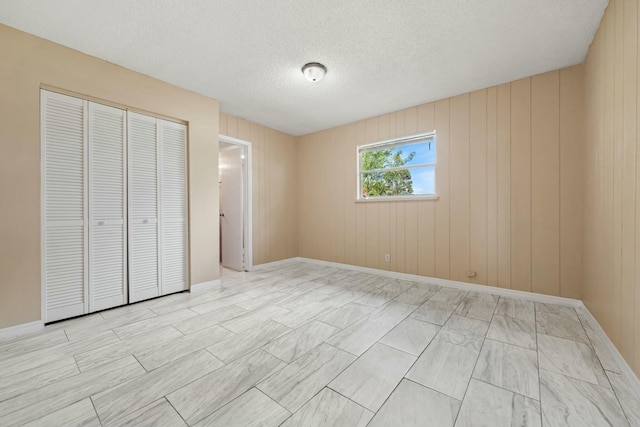 unfurnished bedroom featuring a closet, baseboards, and a textured ceiling