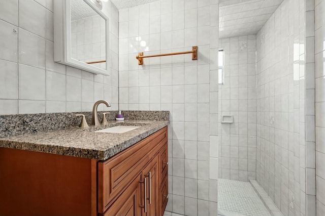 bathroom with vanity, tile walls, and tiled shower