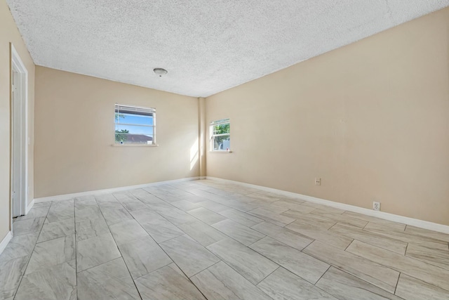 unfurnished room featuring baseboards and a textured ceiling