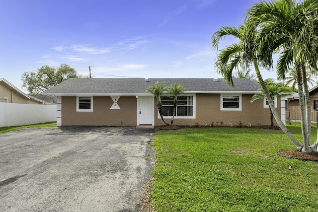 ranch-style home with stucco siding, driveway, a front yard, and fence