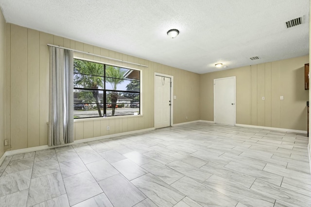 empty room with baseboards, visible vents, and a textured ceiling