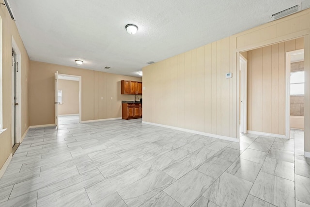 unfurnished living room featuring visible vents, baseboards, and a textured ceiling