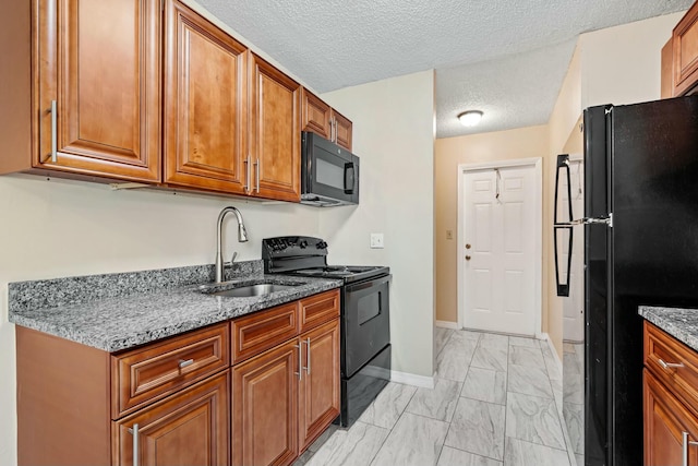 kitchen with dark stone countertops, brown cabinets, marble finish floor, black appliances, and a sink