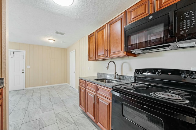 kitchen with brown cabinetry, visible vents, stone countertops, a sink, and black appliances