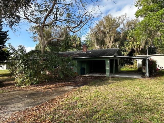 exterior space featuring a carport, driveway, a chimney, and a front yard