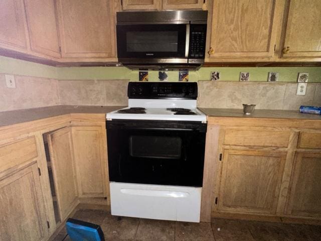 kitchen with dark tile patterned floors, backsplash, light countertops, and electric range oven