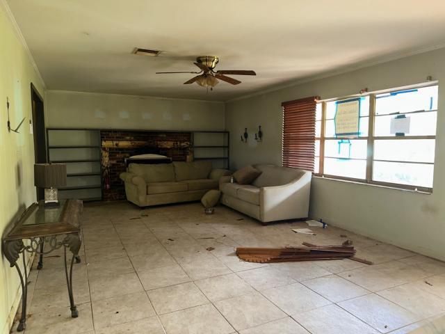 living room with a ceiling fan, visible vents, and ornamental molding