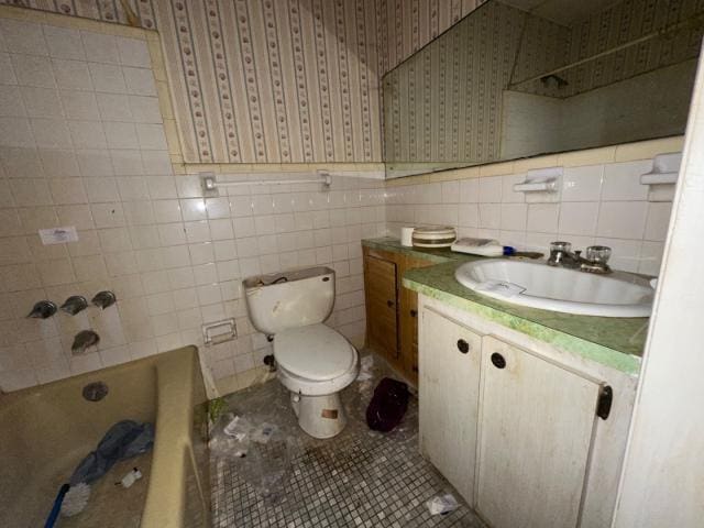 full bath with vanity, wallpapered walls, tile patterned floors, toilet, and tile walls