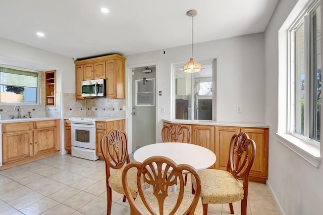 kitchen with electric range, a sink, stainless steel microwave, tasteful backsplash, and light countertops