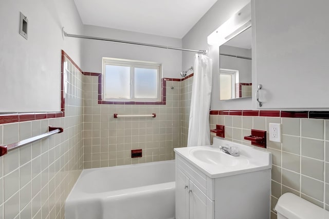 full bathroom featuring vanity, a wainscoted wall, shower / tub combo, tile walls, and toilet