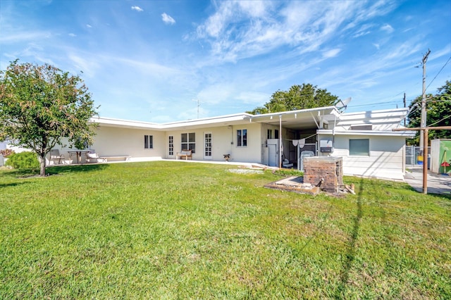 back of house with a yard, a patio, an attached carport, and stucco siding