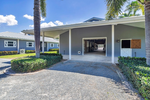 13408 55th St S, Wellington, FL 33449 - view of property exterior featuring an attached carport, gravel driveway, ac unit, and an attached garage