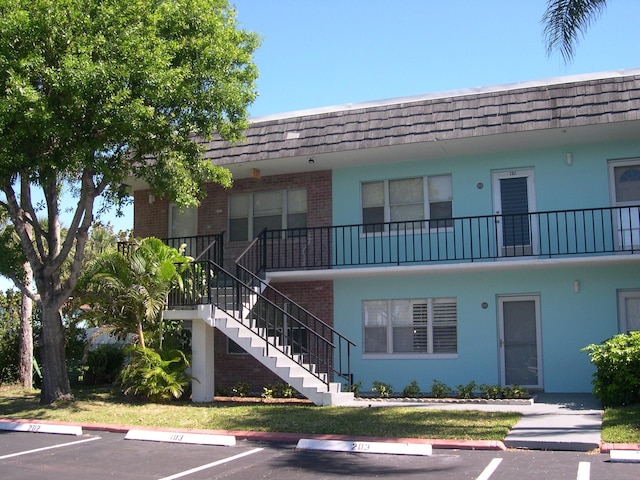 view of building exterior featuring stairway and uncovered parking