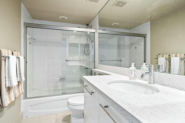 full bathroom featuring tile patterned flooring, visible vents, toilet, shower / bath combination with glass door, and vanity