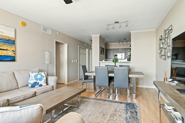 interior space with light wood finished floors, visible vents, crown molding, and baseboards