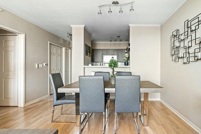 dining room with rail lighting, baseboards, crown molding, and light wood finished floors