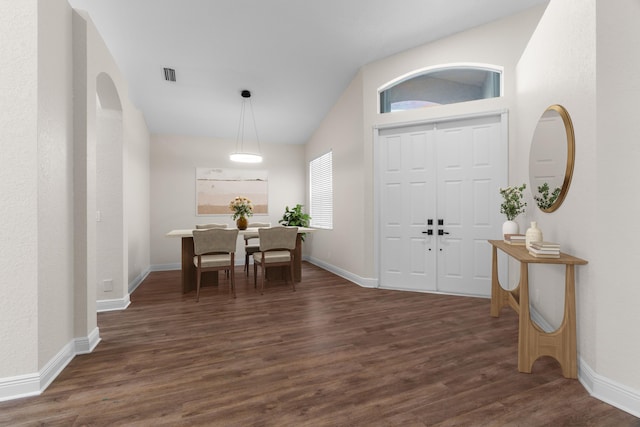 foyer entrance with dark wood-style floors, visible vents, baseboards, and vaulted ceiling