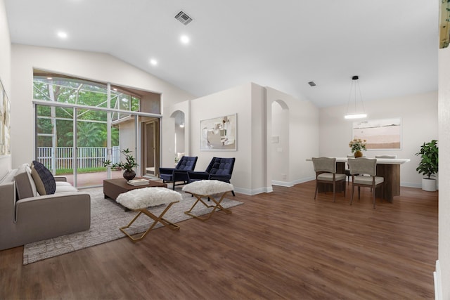 living area with visible vents, wood finished floors, arched walkways, baseboards, and vaulted ceiling