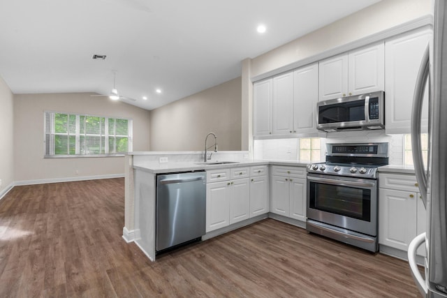 kitchen featuring white cabinetry, vaulted ceiling, appliances with stainless steel finishes, and a sink