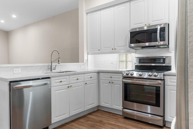 kitchen featuring decorative backsplash, appliances with stainless steel finishes, wood finished floors, and a sink