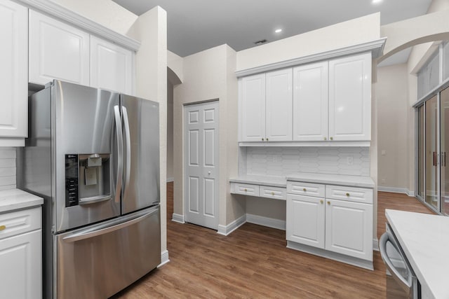 kitchen featuring stainless steel appliances, arched walkways, backsplash, and wood finished floors