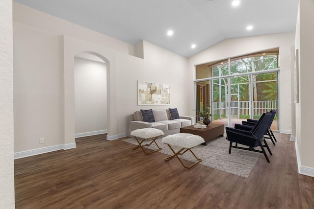 living area featuring baseboards, arched walkways, lofted ceiling, and wood finished floors