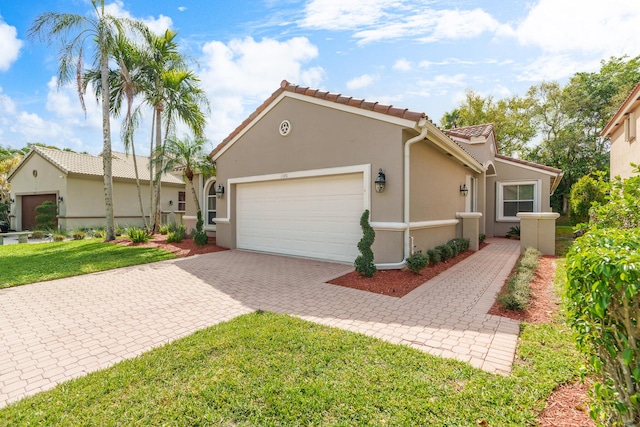 mediterranean / spanish-style house with a front lawn, a tile roof, stucco siding, decorative driveway, and a garage