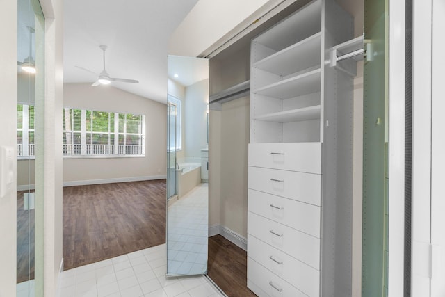 spacious closet with light wood-type flooring, ceiling fan, and vaulted ceiling