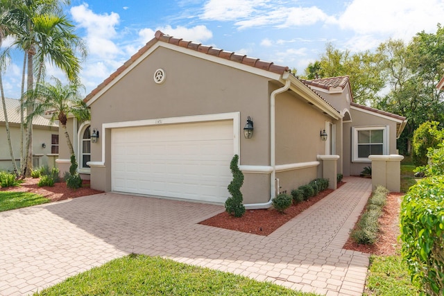 view of home's exterior featuring decorative driveway, a tile roof, an attached garage, and stucco siding