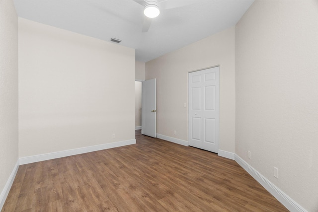 unfurnished bedroom featuring ceiling fan, visible vents, baseboards, and wood finished floors